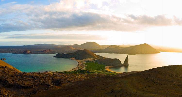 Vue panoramique de l'île Bartolomé avec le Rocher du Pinacle, lumière dorée et paysage volcanique environnant.