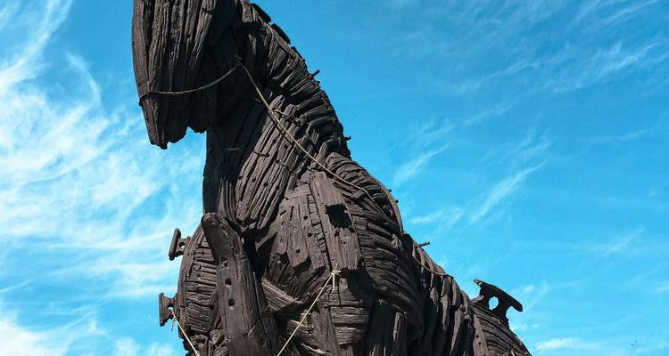 Primer plano de la réplica del Caballo de Troya de madera contra un cielo azul brillante con nubes tenues.