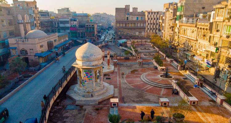 Vue aérienne à l'heure dorée d'une place de ville historique avec monument à coupole, rues et bâtiments environnants.