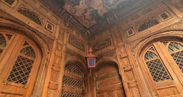 Gros plan de murs en bois sculptés de manière complexe et de fenêtres à treillis à l'intérieur d'un bâtiment patrimonial.