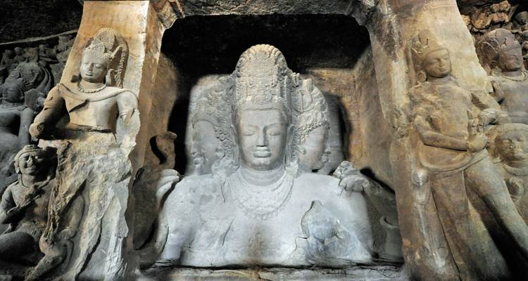 Alte Basaltstatuen hinduistischer Gottheiten, die in die Felswände der Elephanta-Höhlen hineingeschnitzt sind.