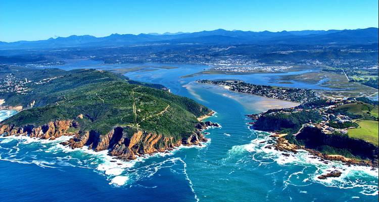 Stunning aerial of a rugged peninsula and turquoise lagoon of the Knysna Heads opening to the ocean.