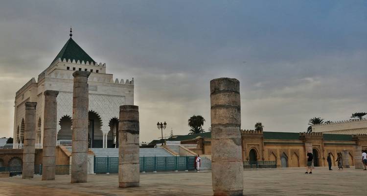 Mausoleum of Mohammed V and surrounding columns under moody evening sky in Rabat.