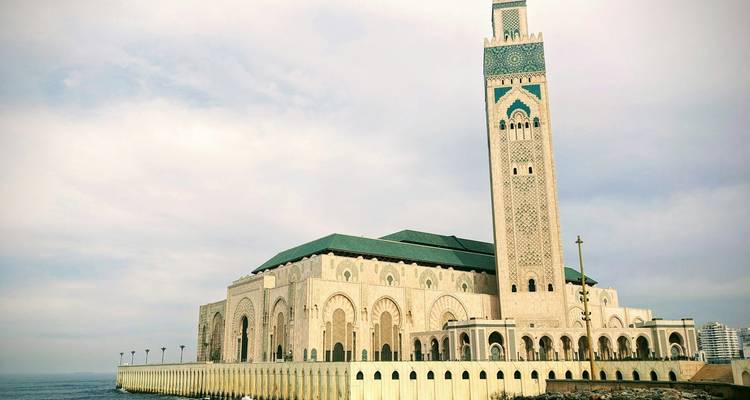Hassan II Mosque stands majestically on the Atlantic shoreline under a pale sky.