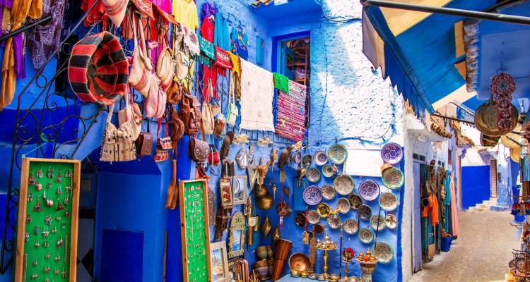 Ruelle du marché de la ville bleue avec artisanat et céramiques exposés sur des murs éclatants.