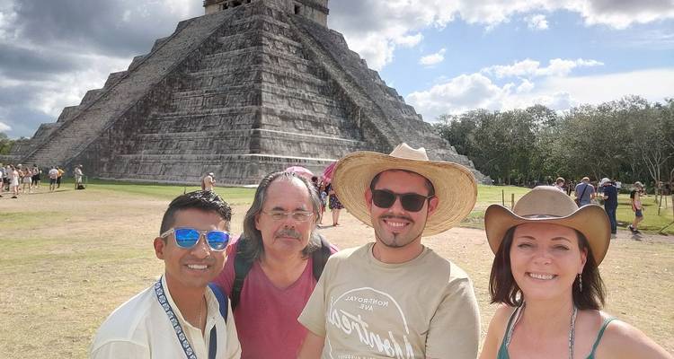 Quatre voyageurs souriants prennent un selfie devant la pyramide à degrés emblématique d'El Castillo à Chichen Itza par une journée ensoleillée.