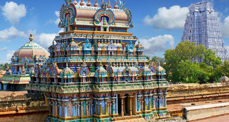 Vibrant, intricately painted gopuram towers of a South Indian temple complex set against a blue sky.