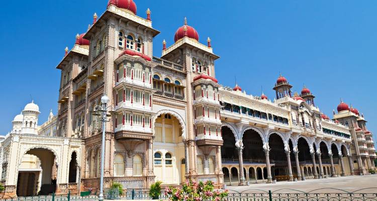Majestic palace with red domes and ornate arches shining against a clear blue sky.