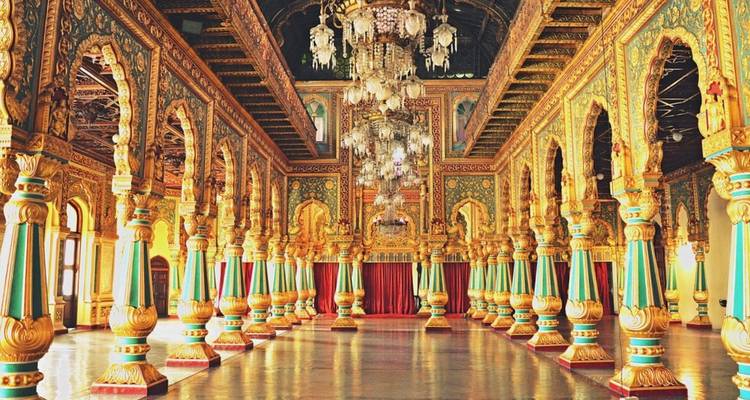 Opulent gilded hall with ornate columns and chandeliers inside Mysore Palace.