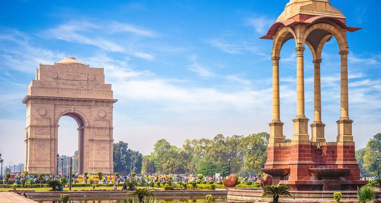 India Gate war memorial and canopy monument surrounded by crowds and gardens.