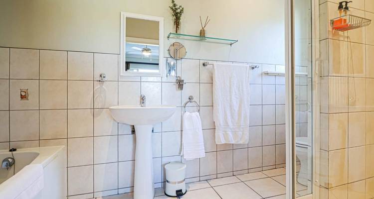 Heldere, schone hotelbadkamer met betegelde muren, console wastafel en frisse witte handdoeken.