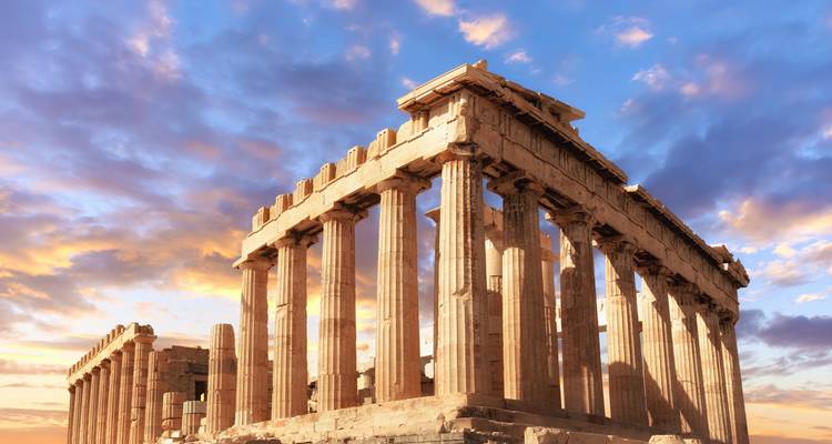 Parthenon ruins glowing in dramatic sunset light against colorful clouds.