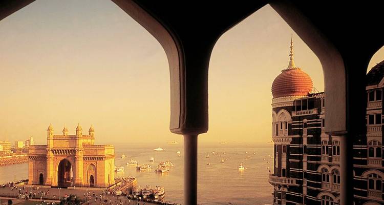 Gateway of India and domed Taj Mahal Palace hotel framed by an arched window at golden hour
