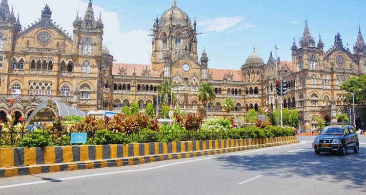 Chhatrapati Shivaji Terminus railway station facade with busy street and car in Mumbai