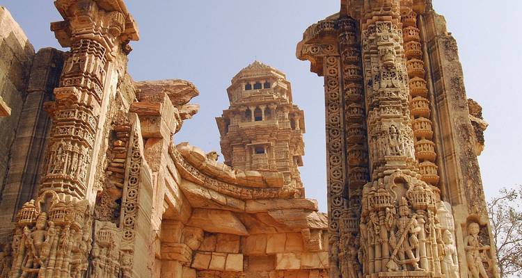 Ornate stone pillars and victory tower ruins of Chittorgarh Fort against clear sky
