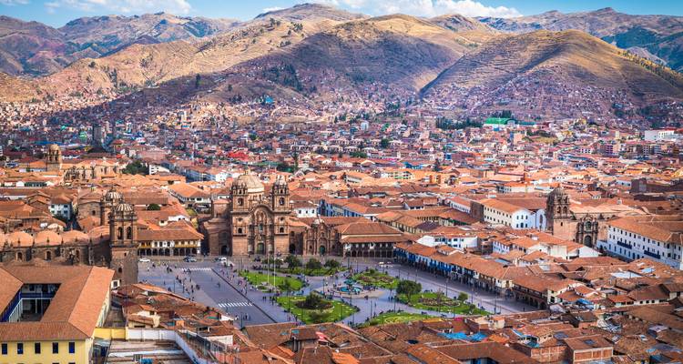 Wide aerial of Cusco’s Plaza de Armas surrounded by terracotta rooftops and Andean mountains