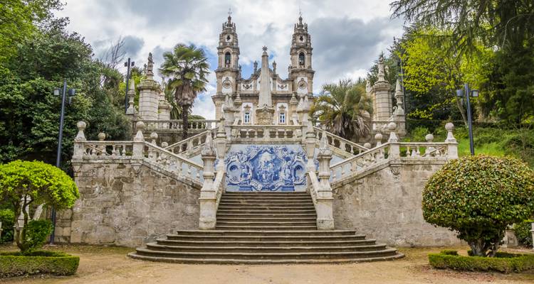 Barok heiligdom bereikbaar via een monumentale granieten trap versierd met blauw-witte azulejo panelen en stenen balustraden.