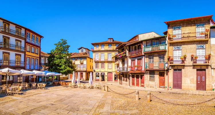 Charmant geplaveide plein omzoomd met kleurrijke vakwerkhuizen en terrasjes in het historische centrum van Guimarães.