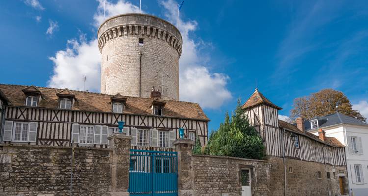 Stenen ronde toren en vakwerkhuizen onder een heldere blauwe hemel