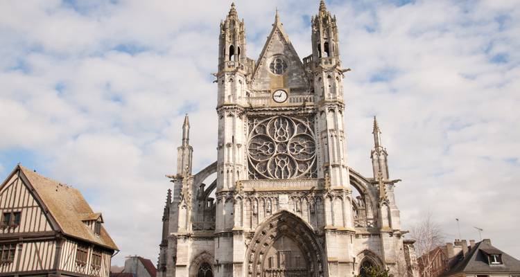 Uitgebreide gotische kerkgevel met grote roosvensters tegen een gedeeltelijk bewolkte hemel