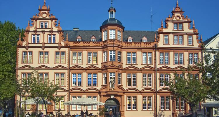 Elegant baroque façade of a city palace with outdoor café tables on a sunny plaza