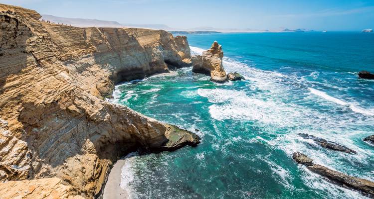 Dramatic sea cliffs and turquoise waters of Paracas National Reserve under clear skies.