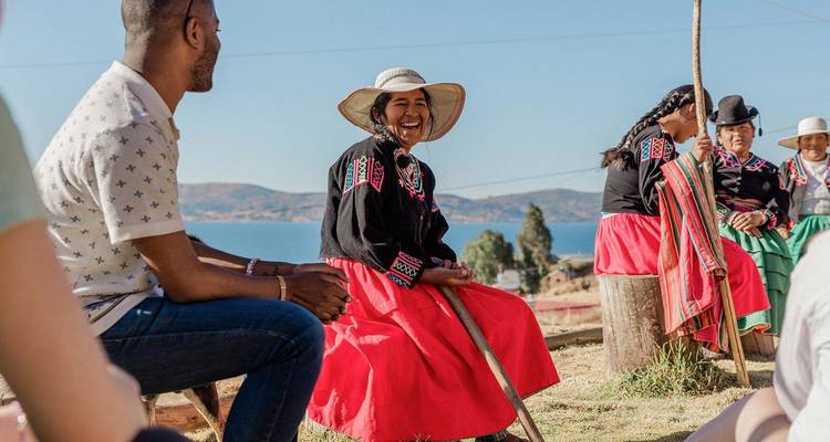 Locals and travellers share stories beside Lake Titicaca, with traditional skirts and hats adding color.