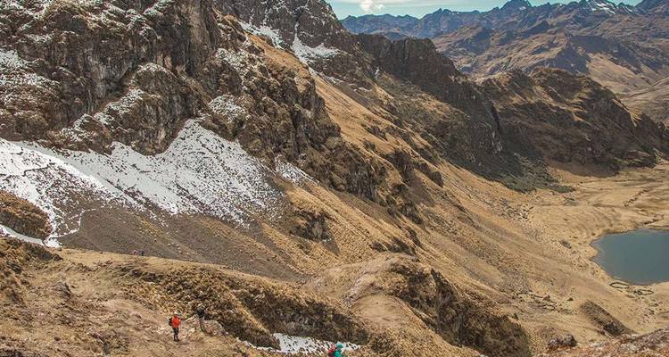 Wandelaars doorkruisen een ruig Andes-bergpad boven een afgelegen alpenmeer.