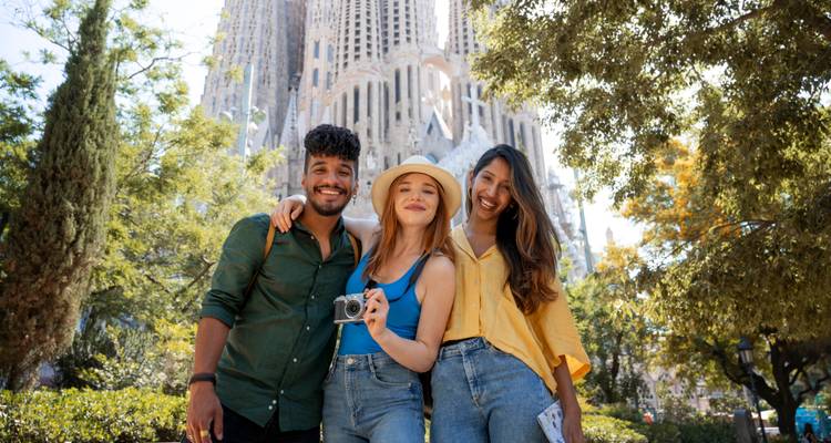 Tres amigos felices posando con una cámara frente a la Sagrada Familia de Barcelona