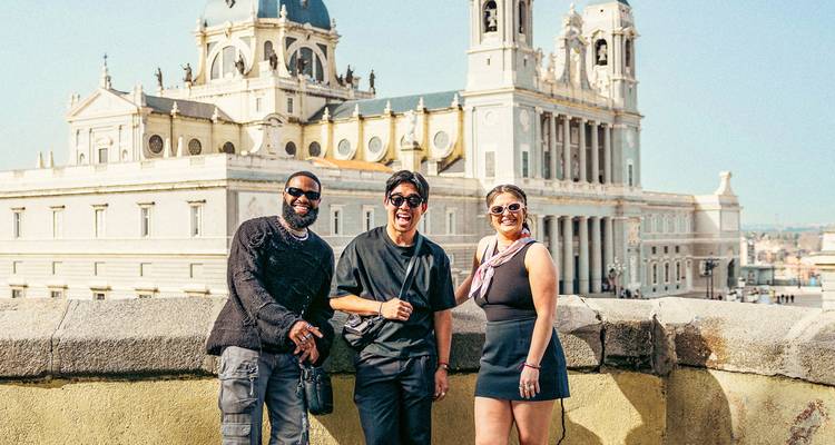 Trois voyageurs joyeux posent avec le saisissant complexe cathédrale-palais de Madrid en arrière-plan.