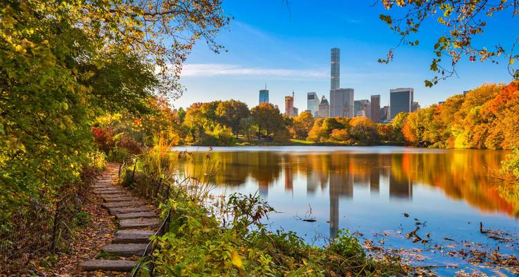 El colorido follaje otoñal enmarca un lago tranquilo con los rascacielos de Nueva York de fondo.