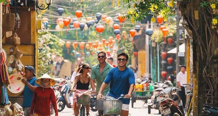Les cyclistes naviguent dans un marché de rue rempli de lanternes dans la vieille ville de Hoi An.