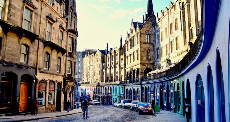 Escaparates curvos y coloridos y adoquines de Victoria Street, Edimburgo con edificios históricos de piedra elevándose por encima.