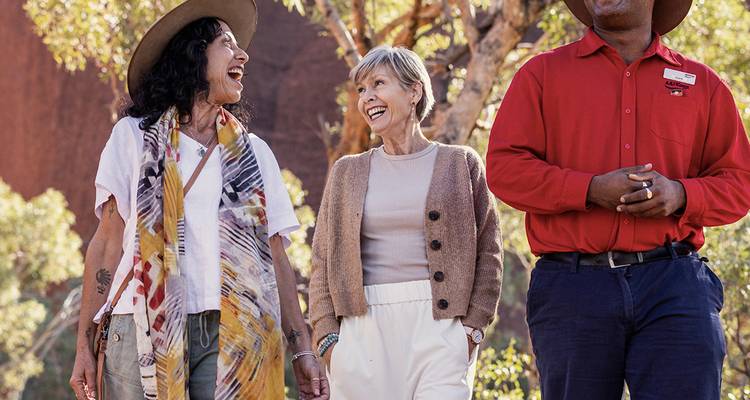Guided cultural walk near Uluru with smiling travellers and Aboriginal host.
