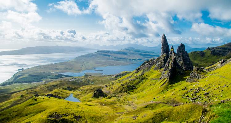 Dramatic green landscape with jagged Old Man of Storr pinnacles overlooking sea lochs