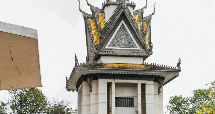 Full view of memorial tower with ornate grey carvings and yellow tiles set against a pale sky.