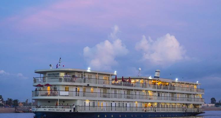 Bateau de croisière fluviale de luxe sur le fleuve Mékong au crépuscule avec un ciel rose.