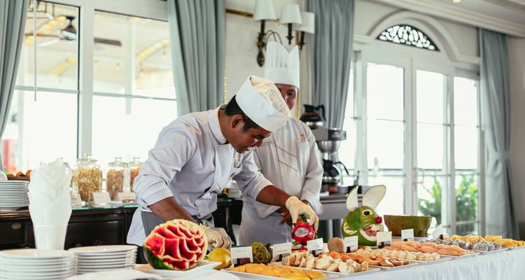 Un chef découpant des fruits et préparant un élaboré buffet de petit-déjeuner à bord.