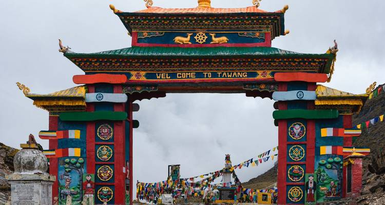 Vibrant ornate gate reading 'Welcome to Tawang' adorned with prayer flags and Himalayan motifs.