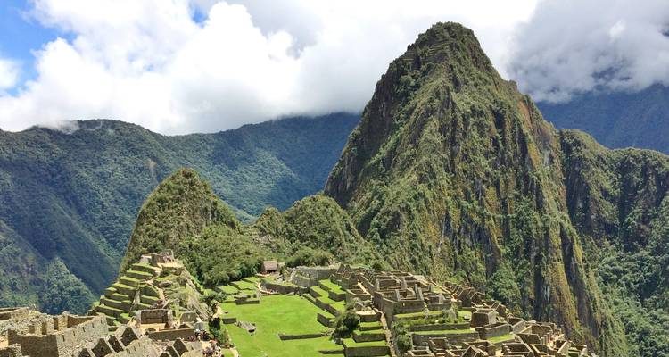 Vue iconique des ruines du Machu Picchu avec un pic vert escarpé qui s'élève derrière.