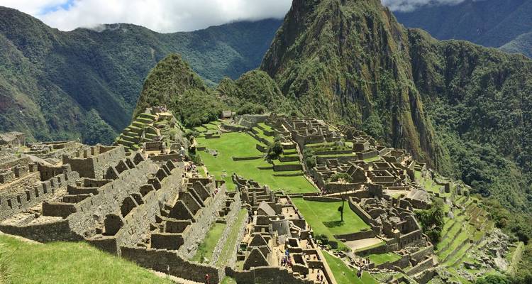 Vue grand angle des terrasses du Machu Picchu et des ruines en pierre sur fond de montagnes andines.