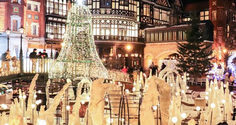 Festive courtyard with illuminated Christmas tree and ornate European-style architecture at night.