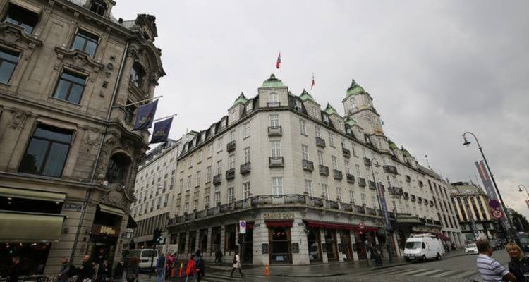 Coin de ville européenne animé avec des bâtiments en pierre ornés et un ciel gris nuageux à Oslo.