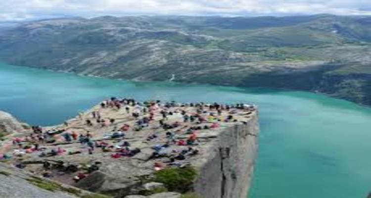 Plateforme bondée au sommet du célèbre rocher de la Chaire de Norvège surplombant un fjord turquoise loin en contrebas.