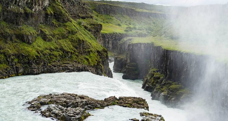Krachtige gletsjerivier stort zich door een groene canyon die gedeeltelijk door mist wordt gesluierd bij de Gullfoss waterval.