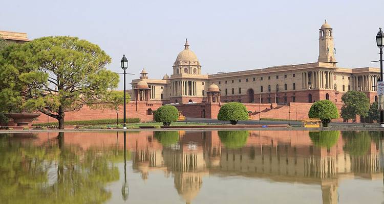 Elegant sandstone government buildings reflected in a tranquil pool within Delhi’s administrative district.