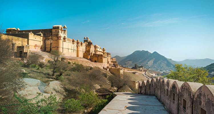 Expansive view of Amber Fort’s sandy-yellow ramparts stretching along a ridge with hills in the background.