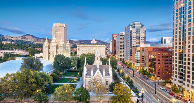 Frühabendliche Stadtansicht der Innenstadt von Salt Lake City mit Temple Square-Gebäuden, eingerahmt von Bergen.