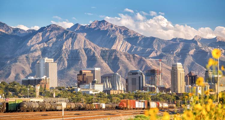Horizonte de Salt Lake City con trenes de carga en primer plano y las imponentes montañas Wasatch al fondo.