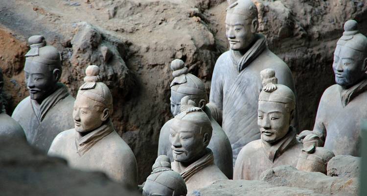 Fila de estatuas icónicas de Guerreros de Terracota parcialmente desenterradas en el pozo de excavación.